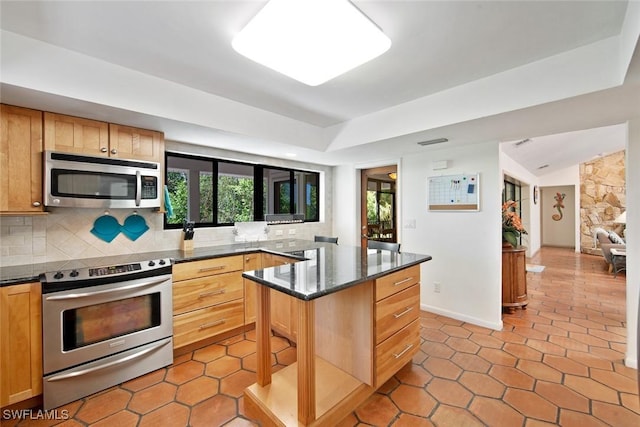 kitchen with dark stone counters, light tile patterned floors, appliances with stainless steel finishes, tasteful backsplash, and a kitchen island