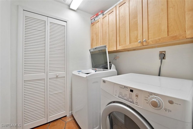 laundry area featuring washer and dryer, light tile patterned flooring, and cabinets