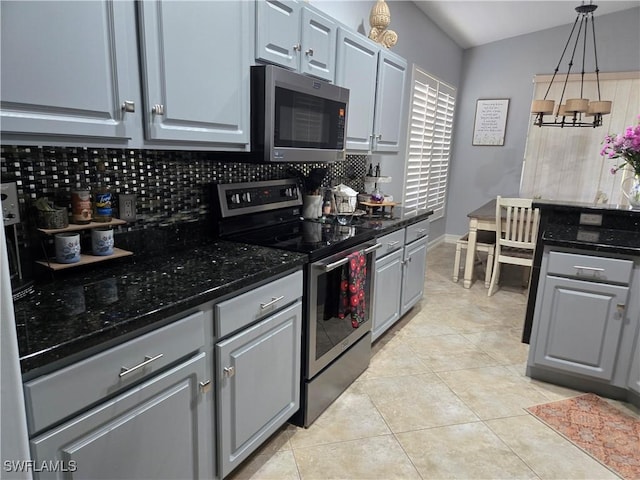 kitchen featuring appliances with stainless steel finishes, backsplash, dark stone counters, pendant lighting, and light tile patterned flooring