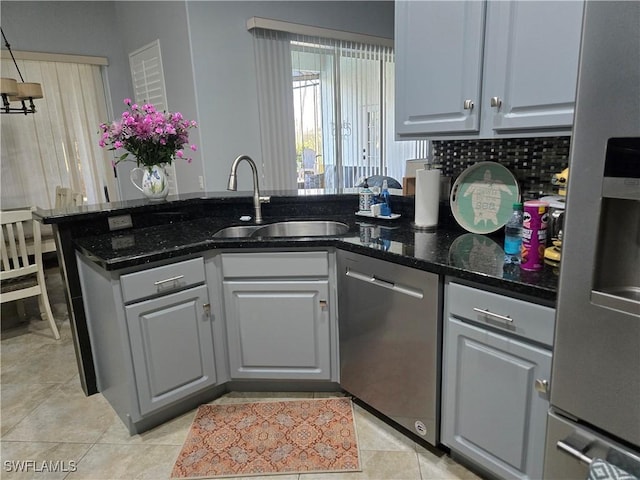 kitchen featuring gray cabinetry, sink, dark stone counters, light tile patterned floors, and appliances with stainless steel finishes