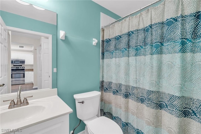 bathroom featuring toilet, vanity, and curtained shower