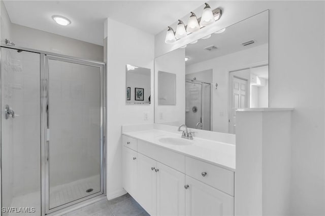 bathroom featuring a shower with shower door, vanity, and tile patterned floors