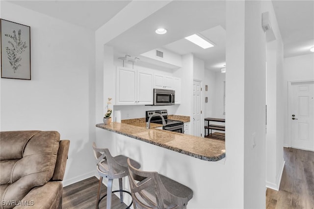 kitchen featuring kitchen peninsula, stainless steel appliances, dark hardwood / wood-style flooring, and white cabinets