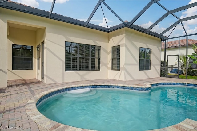 view of swimming pool featuring glass enclosure and a patio area