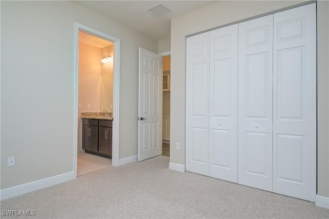 unfurnished bedroom featuring light carpet, connected bathroom, and a closet