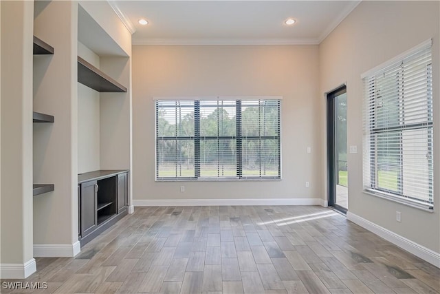 unfurnished living room with light hardwood / wood-style flooring, a wealth of natural light, and ornamental molding