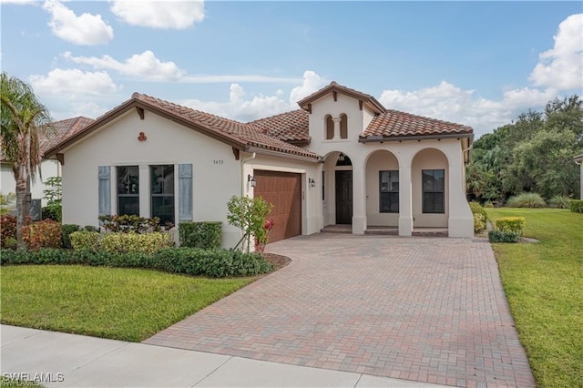 mediterranean / spanish-style house featuring covered porch, a front yard, and a garage