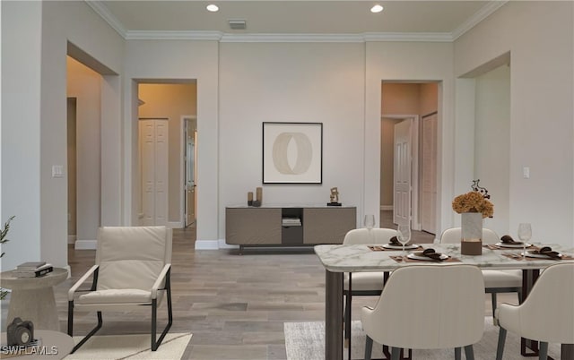 dining space featuring light wood-type flooring and crown molding