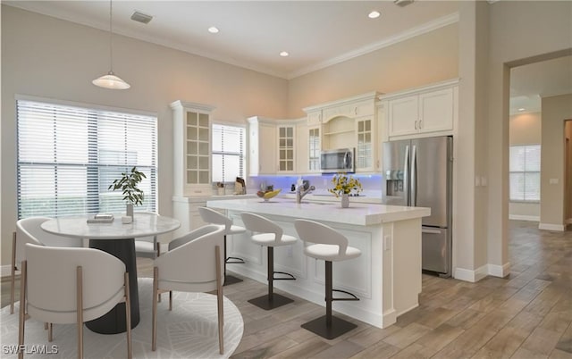 kitchen featuring a kitchen island, light hardwood / wood-style floors, stainless steel appliances, and hanging light fixtures