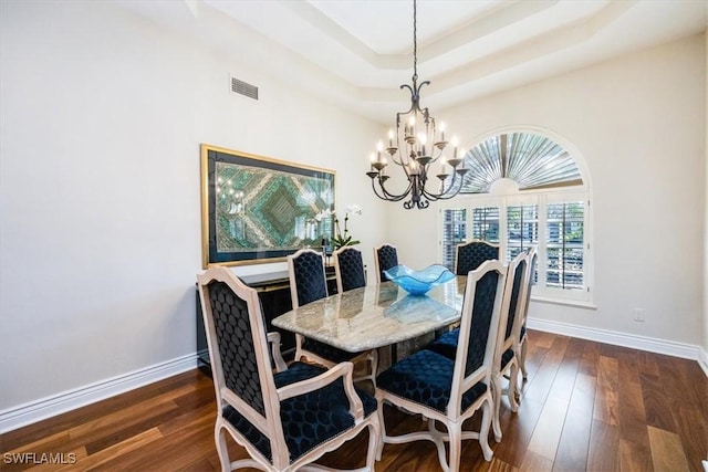 dining room with a raised ceiling, a chandelier, and dark hardwood / wood-style floors