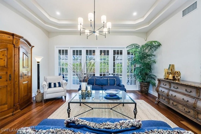 living room with a chandelier, french doors, a tray ceiling, and dark hardwood / wood-style floors