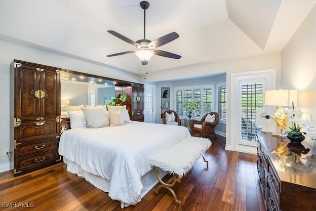 bedroom featuring access to exterior, a raised ceiling, ceiling fan, and dark wood-type flooring