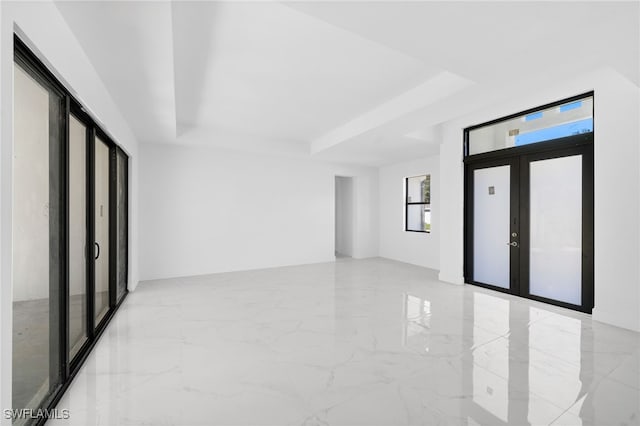 unfurnished room featuring a tray ceiling and french doors