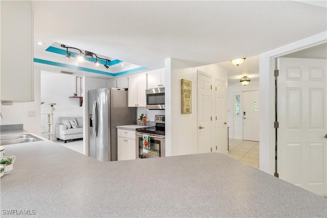 kitchen featuring white cabinetry, sink, stainless steel appliances, a raised ceiling, and light tile patterned floors