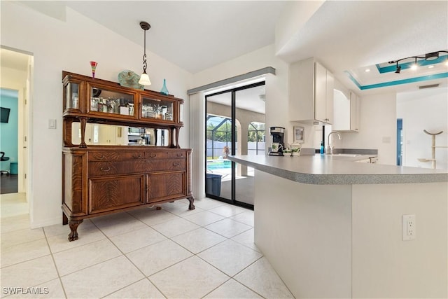 kitchen featuring pendant lighting, sink, light tile patterned floors, white cabinetry, and kitchen peninsula