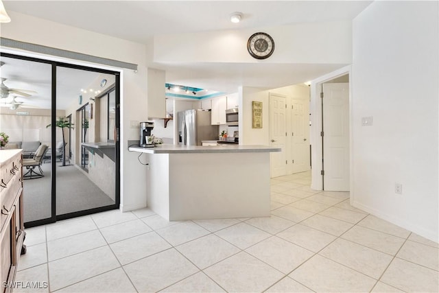 kitchen featuring kitchen peninsula, stainless steel appliances, ceiling fan, white cabinets, and light tile patterned flooring