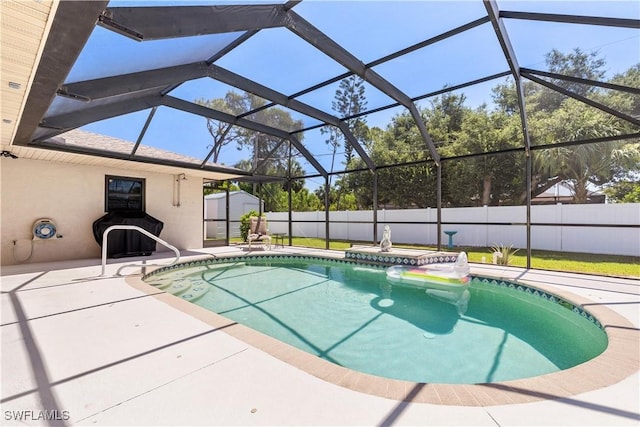 view of pool featuring glass enclosure, a patio, and a storage shed