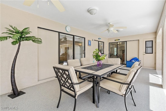 carpeted dining room with ceiling fan