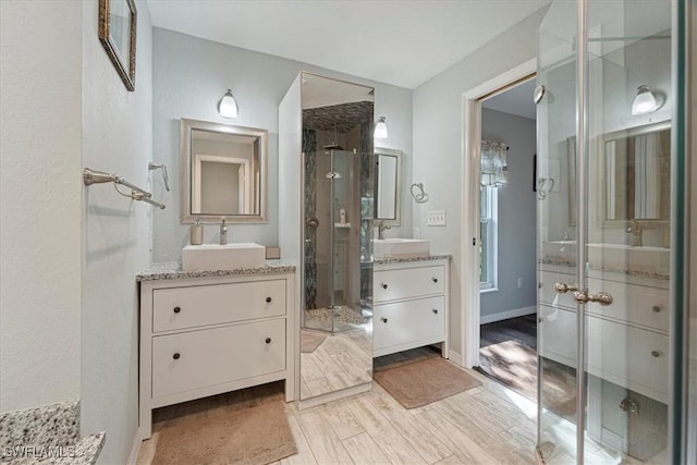 bathroom with hardwood / wood-style floors, vanity, and a shower with door