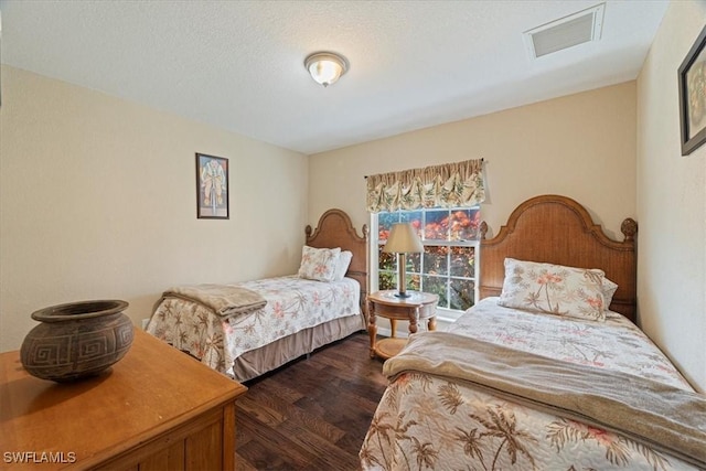 bedroom with dark hardwood / wood-style floors and a textured ceiling