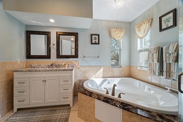 bathroom featuring tile patterned flooring, vanity, tile walls, and tiled bath