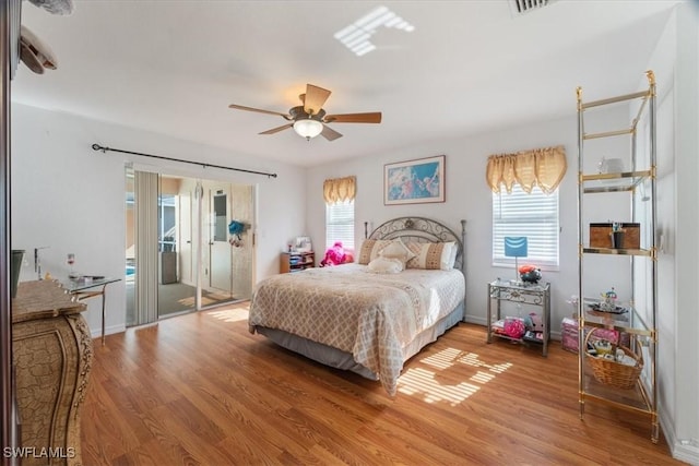 bedroom with ceiling fan, wood-type flooring, and multiple windows