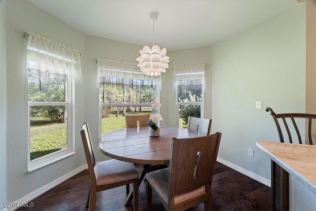 dining room featuring dark wood-type flooring, a wealth of natural light, and a notable chandelier