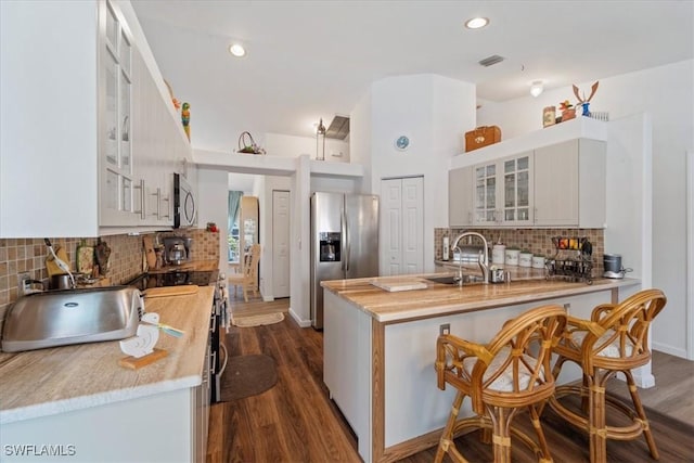 kitchen with wooden counters, stainless steel appliances, dark wood-type flooring, sink, and white cabinets