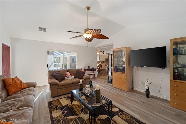 living room featuring ceiling fan, hardwood / wood-style floors, and vaulted ceiling