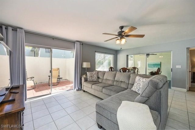 living area with a ceiling fan, baseboards, and light tile patterned floors