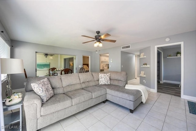 living room with a ceiling fan, visible vents, baseboards, and light tile patterned floors