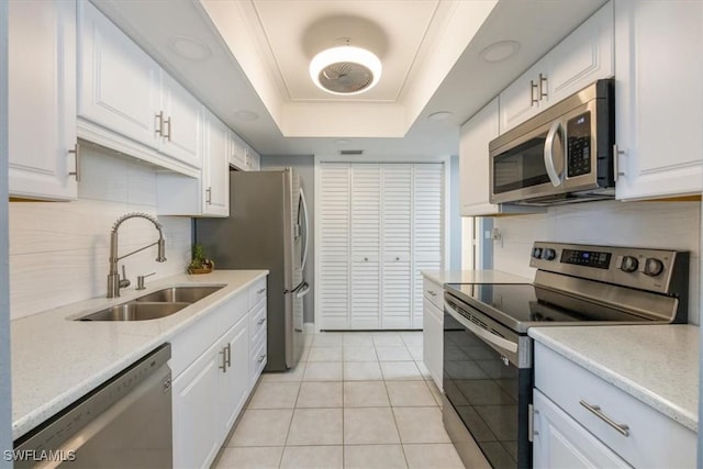 kitchen featuring a sink, appliances with stainless steel finishes, a raised ceiling, and white cabinetry