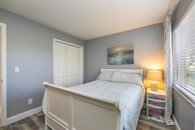 bedroom with dark wood-style floors, baseboards, and a closet