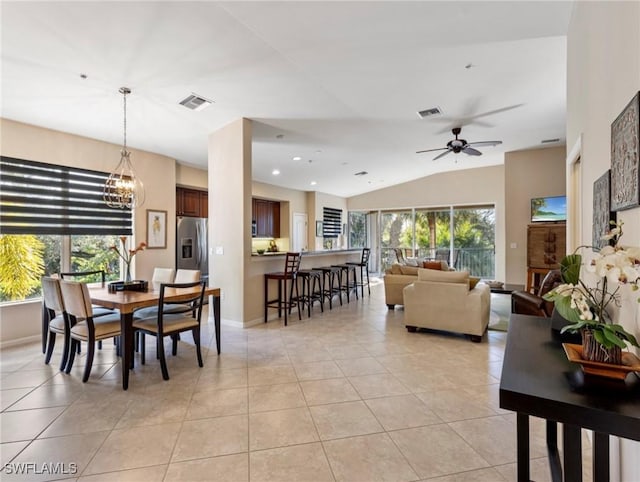 dining area featuring ceiling fan with notable chandelier, vaulted ceiling, and light tile patterned flooring