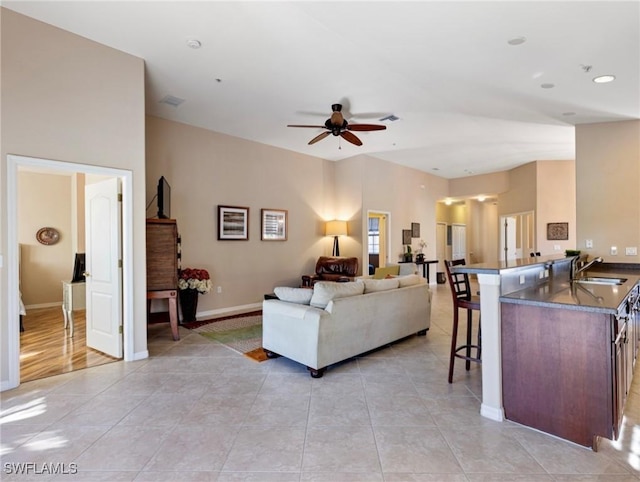 tiled living room featuring ceiling fan and sink