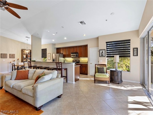 living room featuring light tile patterned floors and ceiling fan with notable chandelier