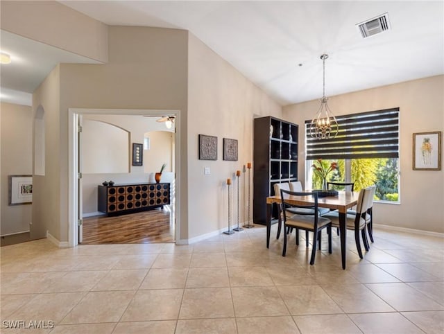 tiled dining area featuring ceiling fan with notable chandelier and lofted ceiling