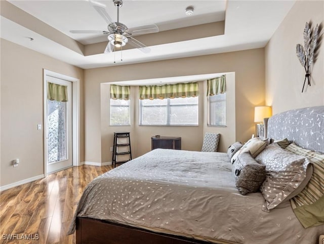 bedroom with a raised ceiling, ceiling fan, and hardwood / wood-style floors