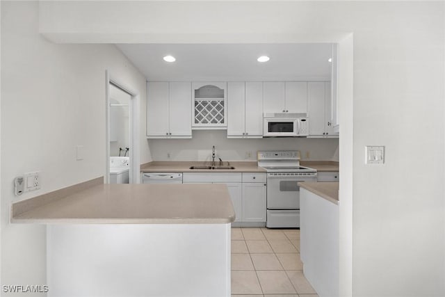 kitchen with white appliances, sink, white cabinets, washer / clothes dryer, and light tile patterned flooring