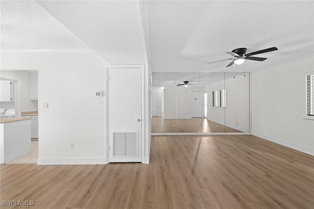 unfurnished living room featuring a textured ceiling, light wood-type flooring, and ceiling fan