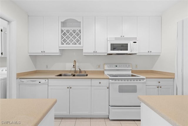 kitchen with white appliances, sink, light tile patterned floors, white cabinets, and washer / dryer