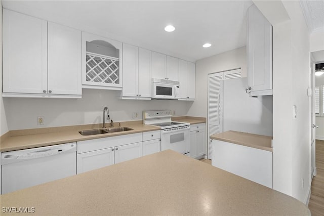 kitchen featuring sink, white cabinets, light hardwood / wood-style floors, and white appliances