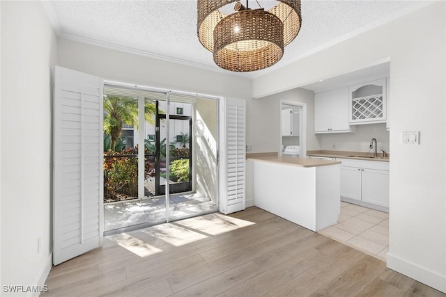 kitchen with white cabinetry, a textured ceiling, and light wood-type flooring