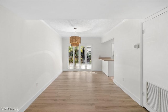 unfurnished dining area with light wood-type flooring and a textured ceiling