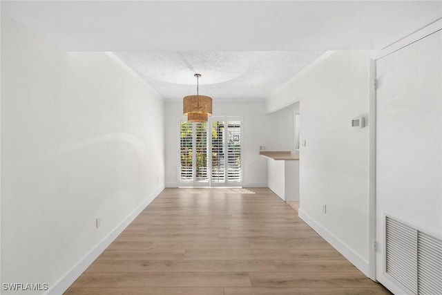 788 Park Shore Dr Unit B17, Naples, FL 34103 - unfurnished dining area featuring a textured ceiling, light wood finished floors, baseboards, and ornamental molding