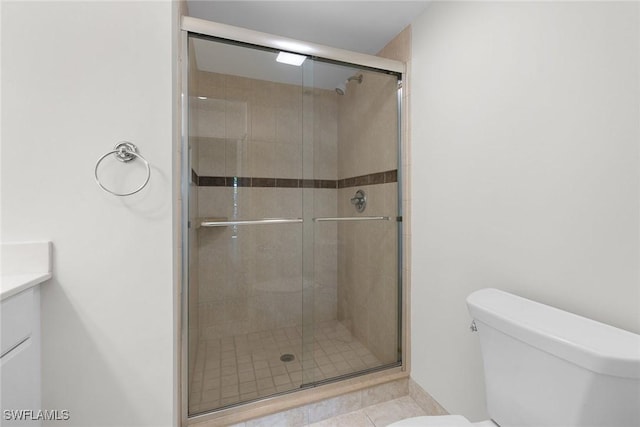 bathroom with tile patterned flooring, vanity, a shower with shower door, and toilet