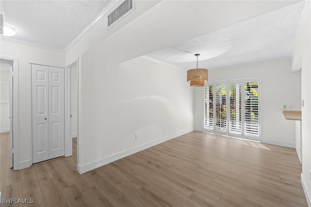 unfurnished room with a textured ceiling, light hardwood / wood-style flooring, and crown molding