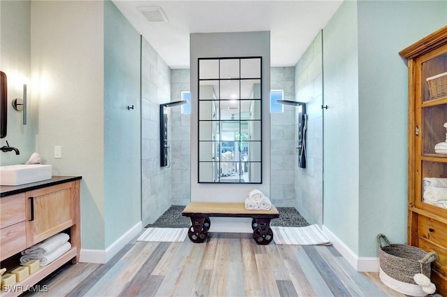 bathroom with vanity, a tile shower, and wood-type flooring