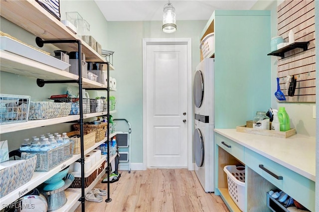 clothes washing area with stacked washer / dryer and light wood-type flooring