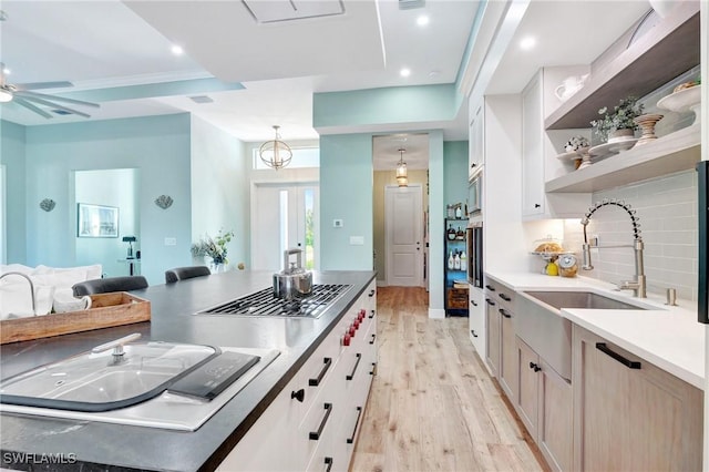 kitchen featuring sink, white cabinets, hanging light fixtures, and light hardwood / wood-style floors